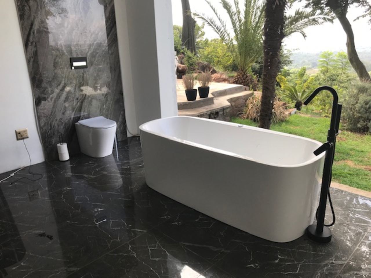 Luxury freestanding bath with matte black mixer and floor tiling